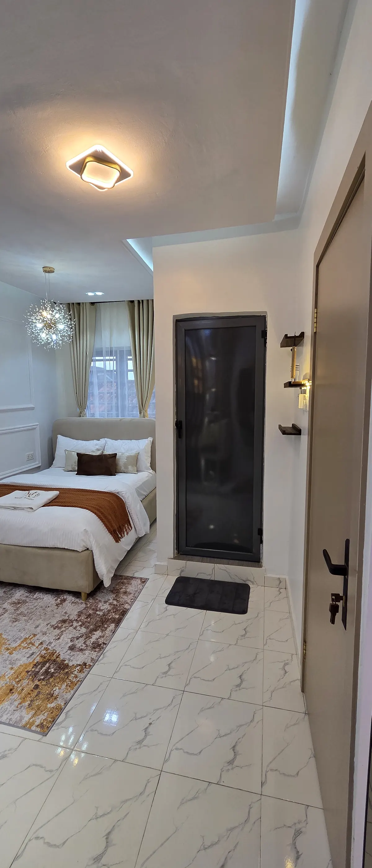 Bedroom with upholstered bed, rust throw and patterned rug seen from the hallway
