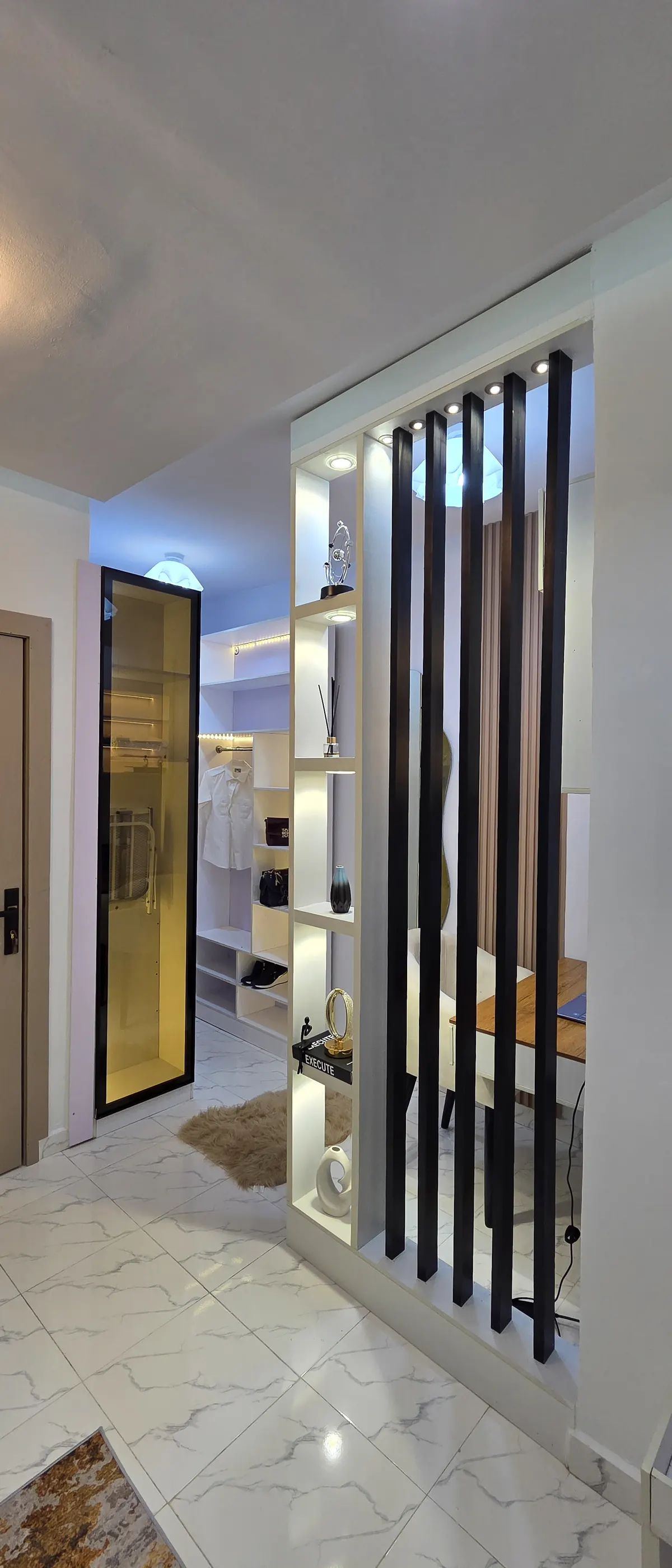 Living area with lit display shelving behind a black slatted partition