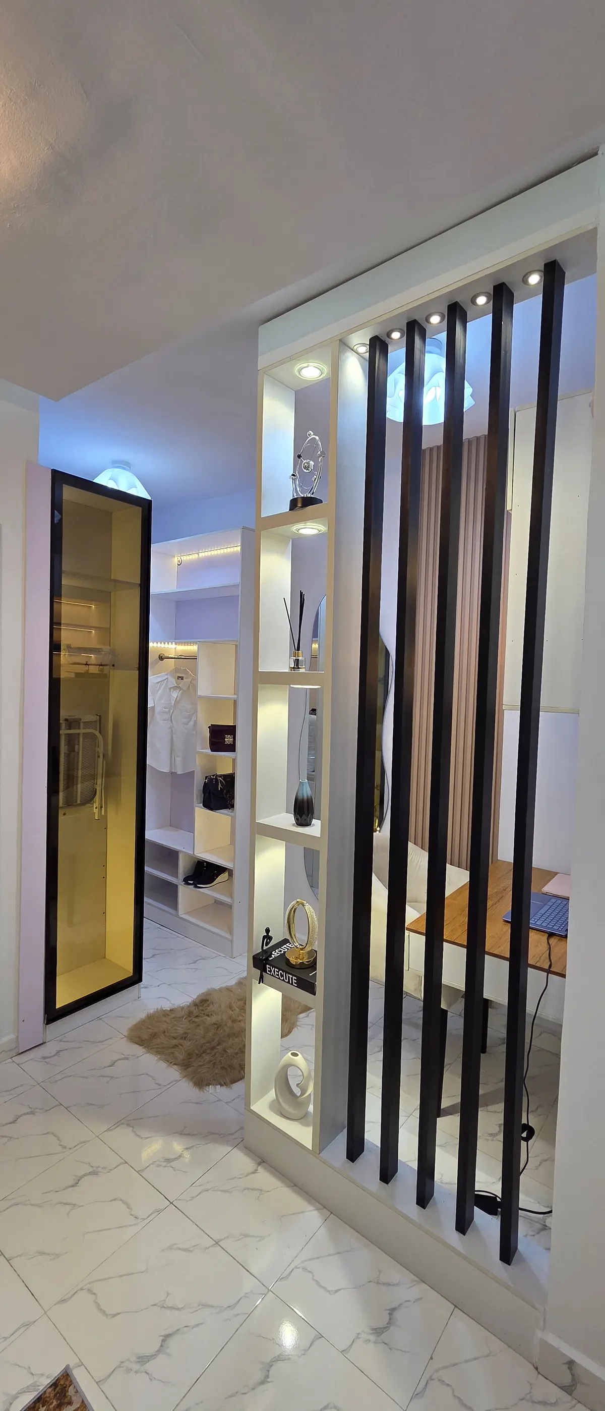 Living space with lit shelving, sheepskin rug and marble floor