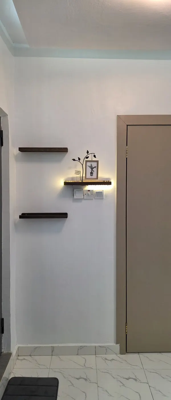Floating walnut shelves with warm accent lighting and a framed print