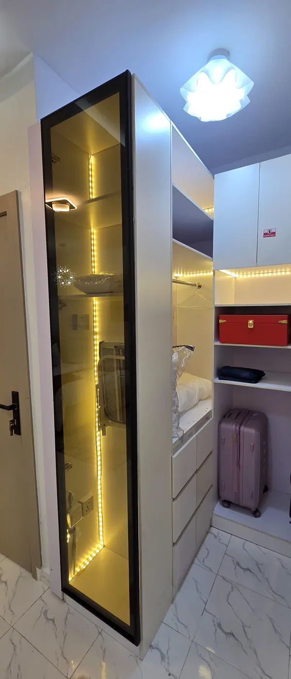 Glass-fronted wardrobe glowing with warm LED strip lighting